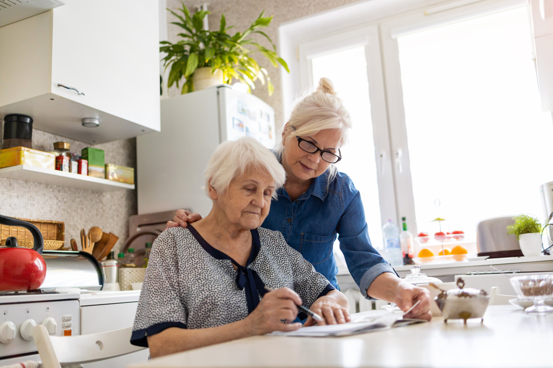Female caregiver assisteing her mother with paperwork in a Traditions of Deerfield assisted living apartment